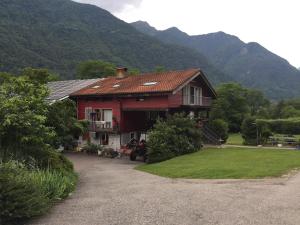 Ein großes rotes Haus mit Bergen im Hintergrund in der Unterkunft Tiny farm studio in Maggia
