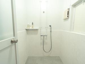 a white bathroom with a shower with a glass door at By The Tree Room in Amami +32 photos