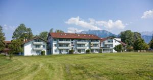 a large house on a field with mountains in the background at Wellness Ferienwohnung mit Hallenbad und Sauna in Oberaudorf