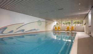 a swimming pool with yellow chairs in a building at Wellness Ferienwohnung mit Hallenbad und Sauna in Oberaudorf