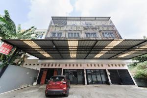 a red car parked in front of a building at RedDoorz Lotte near PTC MALL in Palembang