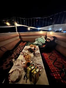 a person sitting on a boat with a table with food at Almani yurt camp in Tong
