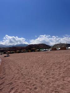 a sandy beach with houses and mountains in the background at Almani yurt camp in Tong +8 photos