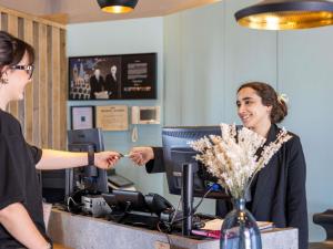 a woman is handing a customer a credit card at ibis Montauban in Montauban +140 photos