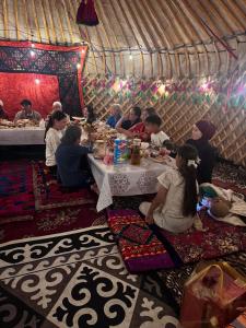 a group of people sitting at a table in a yurt at Almani yurt camp in Tong
