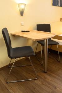 einen Holztisch mit zwei Stühlen in einem Zimmer in der Unterkunft Euro Youth Hotel Munich in München