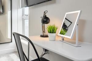 a white desk with a mirror and a lamp at Cosy Two Bed House (16BLR) in Leeds