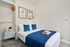 a bedroom with a bed with blue and white sheets at Cosy Two Bed House (16BLR) in Leeds