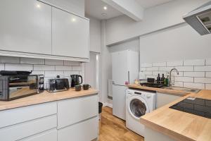 a kitchen with white cabinets and a washing machine at Cosy Two Bed House (16BLR) in Leeds +18 photos