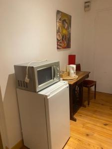 a microwave on top of a refrigerator next to a table at Chambre avec TV au calme in Pontgouin
