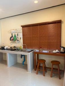 a kitchen with a sink and a counter with two stools at PnppGreenhill in Ko Phangan