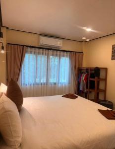 a bedroom with a large white bed with a window at PnppGreenhill in Ko Phangan