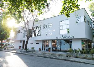 a white building with a tree in front of it at Hotel Barbacoa Apartadó in Apartadó