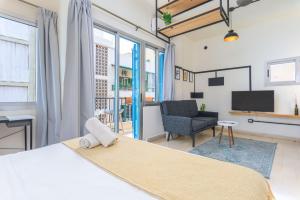 a bedroom with a bed and a chair and a television at Factory Studio in Mar Mikhael in Al Mudawwar