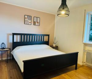 ein Schlafzimmer mit einem schwarzen Bett und einer Pendelleuchte in der Unterkunft Panoramapause in Wertach