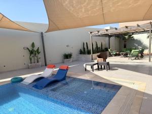a swimming pool with two chairs and a table at Muzn al Ghaith Luxury Chalet with Private Pool in Ash Shāghūr