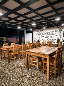 a group of wooden tables and chairs in a room at Snooze hostel lombok in Selong Belanak