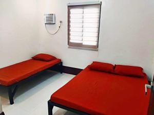 a room with two red beds and a window at ljp farm resort couple rooms in Tigaon