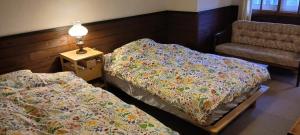two beds in a room with a lamp and a chair at Cafe&ResortInn VAIRGO in Hoki