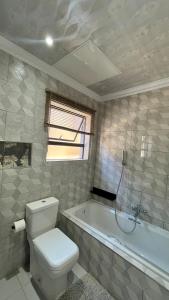 a bathroom with a toilet and a bath tub at Yolaan Guesthouse in Sterkspruit +9 photos