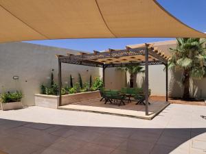 a wooden pergola with a picnic table on a patio at Muzn al Ghaith Luxury Chalet with Private Pool in Ash Shāghūr
