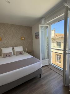 a bedroom with a bed and a large window at Hôtel The Originals Miramar, Royan Pontaillac in Royan