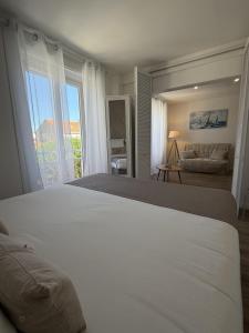 a bedroom with a large white bed and a couch at Hôtel The Originals Miramar, Royan Pontaillac in Royan