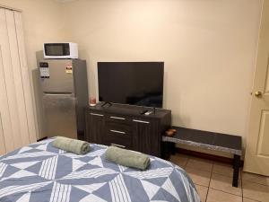 a bedroom with a bed and a tv and a dresser at Broome Rest House in Broome