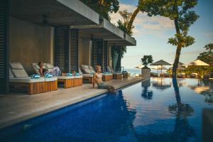 a man sitting on the edge of a swimming pool at a resort at Los Altos Resort in Manuel Antonio