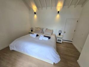 a bedroom with a large white bed with two pillows at Varadouro Cove House in Horta