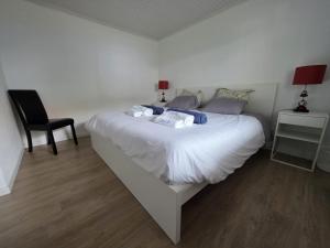a bedroom with a large white bed with a black chair at Varadouro Cove House in Horta +29 photos