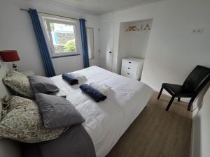a bedroom with a white bed with pillows and a chair at Varadouro Cove House in Horta