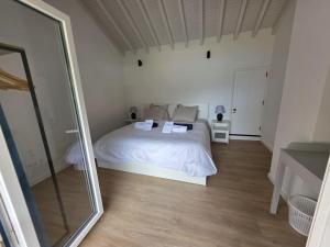 a bedroom with a white bed and a mirror at Varadouro Cove House in Horta