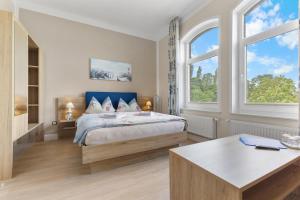 a bedroom with a bed and two windows at Hotel Norden Norddeich in Norddeich