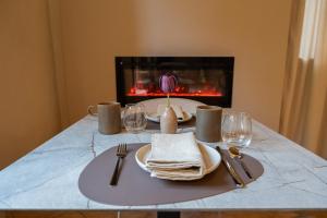 a table with plates and forks and napkins and a fireplace at Alnus in Valentano