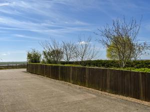 a wooden fence next to a road with trees at Ivy No1 - Uk49251 in Althorne