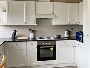 a kitchen with white cabinets and a stove top oven at Ivy No1 - Uk49251 in Althorne