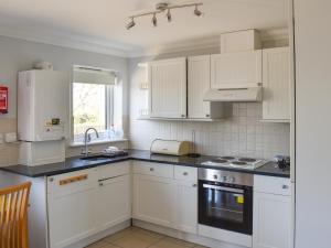 a kitchen with white cabinets and black counter tops at Thistle No4 - Uk49250 in Althorne