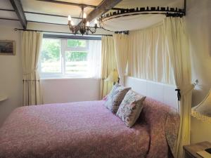 a bedroom with a bed and a window at Kilcummer Stables in Tintagel