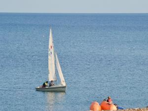 a small sail boat in the water with people on it at Thalassa in Pagham