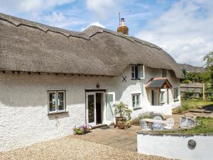 a thatched cottage with a bench in front of it at Four Oaks in Bransgore
