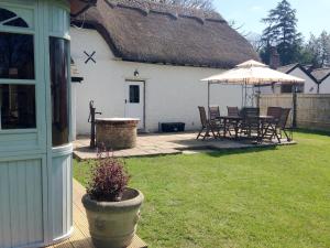 a house with a patio with a table and an umbrella at Four Oaks in Bransgore
