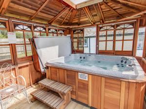 a jacuzzi tub in a wooden house with a bench at Four Oaks in Bransgore