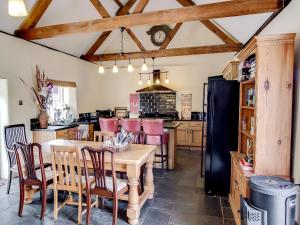a kitchen with a table and chairs and a refrigerator at Four Oaks in Bransgore