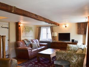 a living room with leather furniture and a tv at Four Oaks in Bransgore +9 photos