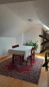 a dining room with a table and chairs on a rug at Nagy Ildikó Vendégház in Lăzarea