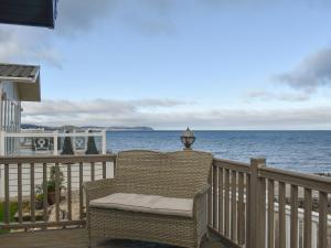 a wicker chair sitting on a balcony overlooking the ocean at Sunset Lodge in Llanddulas