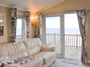 a living room with a couch and a view of the ocean at Sunset Lodge in Llanddulas