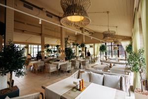 a restaurant with white tables and chairs and plants at Bartolomeo in Dnipro