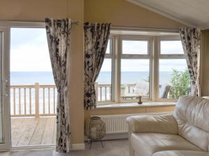 a living room with a couch and a view of the ocean at Sunset Lodge in Llanddulas +10 photos